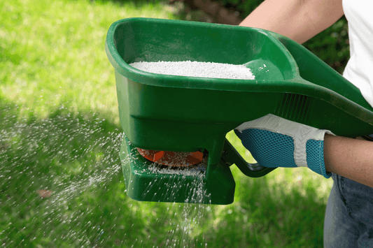 hand fertiliser spreader being operated with fertiliser product inside 