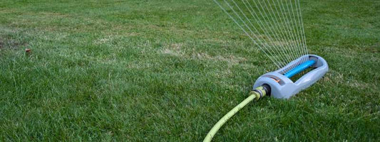 Garden sprinkler watering a green lawn during a dry summer spell